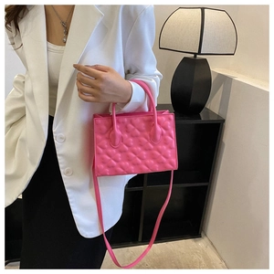 Chic pink crossbody bag with embossed heart pattern styled on a white blazer model
