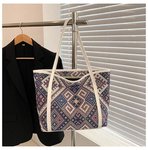Close-up of ethnic geometric woven tote bag with colorful diamond patterns and white handles