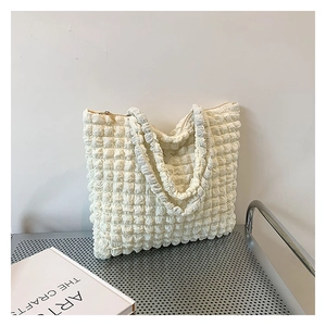 Dettaglio del tessuto bianco a bolle su una borsa tote capiente con cerniera