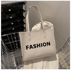 Detail of beige tote bag with black FASHION print inside a metal shopping cart