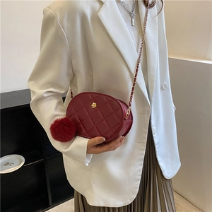 Chic burgundy quilted oval crossbody bag with gold chain strap and floral accent