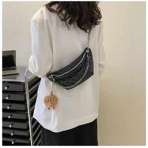 Detail of quilted fanny pack featuring chunky black chains and a cute plush bear charm
