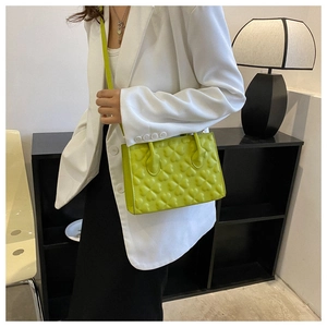 Detail of neon green crossbody bag featuring embossed clover pattern and top handle