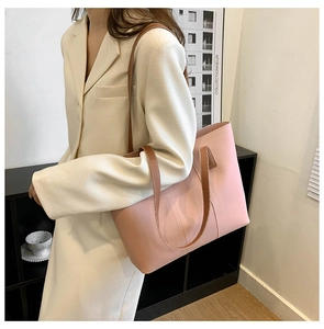 Detail of pink large capacity tote bag with brown straps worn on a beige blazer