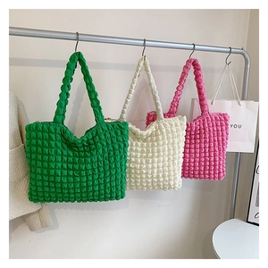 Tre borse tote colorate con trama a bolle in verde bianco e rosa appese a un'asta