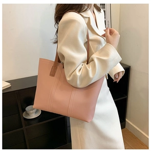 Close-up of pink tote bag with brown straps and white contrast stitching detail