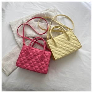 Close-up of embossed clover pattern on pink and beige textured leather crossbody bags