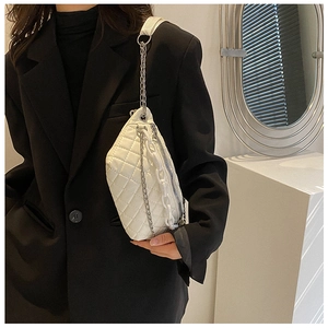 Close-up of white quilted crossbody bag with stylish chunky acrylic and metal chains