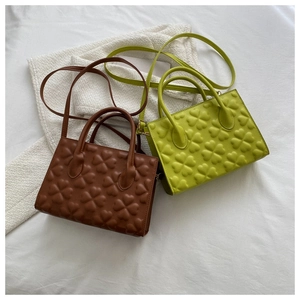 Detail of four-leaf clover embossed pattern on retro brown and green PU leather handbags
