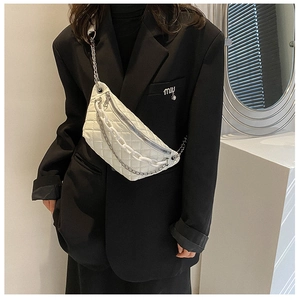 Detail of white quilted fanny pack with double chains worn on a black blazer