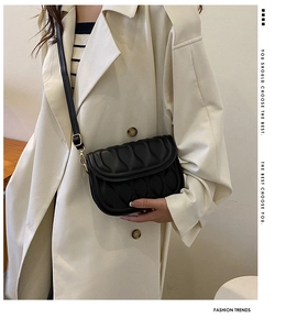 Detail of black quilted crossbody bag with wave texture and gold metal hardware
