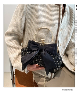 Detail of tweed crossbody bag featuring a large satin bow and golden metal handle