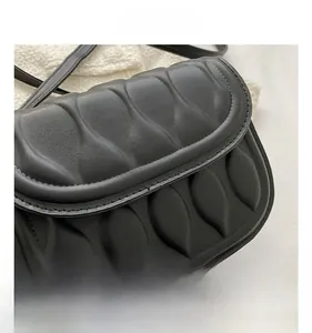 Macro detail of black pleated faux leather bag showing wavy texture and stitching
