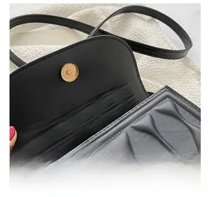 Close-up of golden magnetic buckle on black quilted leather crossbody shoulder bag
