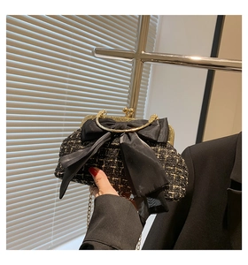 Detail of tweed evening clutch with large satin bow and golden metal handle