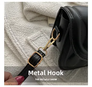 Close-up of golden hardware hook and adjustable strap on black quilted leather bag
