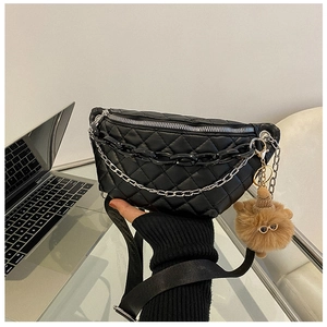 Detail of black quilted waist bag with silver zipper, acrylic chains and plush bear charm
