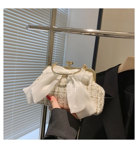 Detail of white tweed evening clutch with chiffon bow and gold ring handle