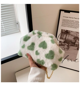 Dettaglio della borsa in peluche bianca con cuori verdi e tracolla a catena d'oro