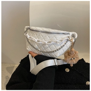 Close-up of white quilted waist bag with acrylic chains and a cute plush bear charm