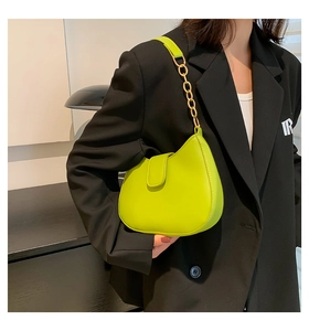 Détail du sac baguette vert fluo en cuir brillant avec bandoulière chaîne dorée