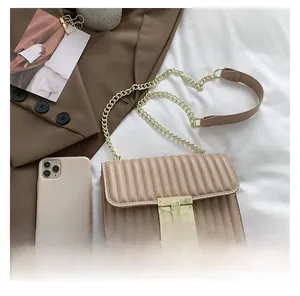 Detail der beigen gesteppten Umhängetasche mit Goldschloss und Kette auf einem Blazer