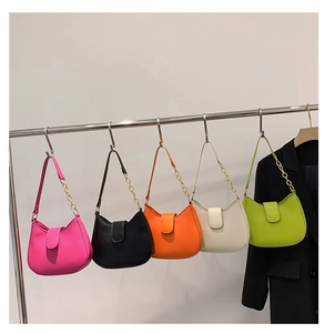 Détail de sacs à main demi-lune colorés avec bandoulières en chaîne sur un présentoir