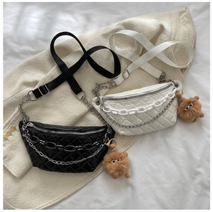 Detail of chic quilted waist bags in black and white with chain decor and plush pendant