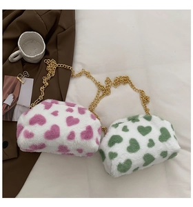 Dettaglio delle borse in peluche con motivo a cuori rosa e verdi e catena dorata