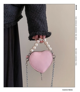 Détail du petit sac coeur en cuir rose clair avec poignée en perles et chaîne argentée