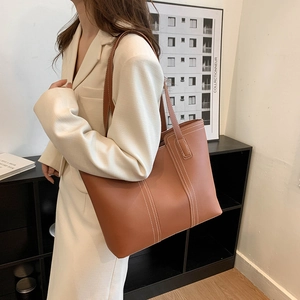 Minimalist tan leather tote bag with white contrast stitching for stylish commuting