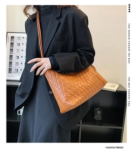 Close-up of caramel quilted tote bag with diamond stitching on a model's shoulder