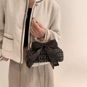 Black and white tweed crossbody bag featuring a large chiffon bow and gold chain strap