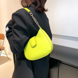 Sac hobo vert néon minimaliste avec chaîne dorée élégante porté à l'épaule par un mannequin