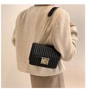 Detail der schwarzen Stepptasche mit goldener Kette und metallischem Drehverschluss