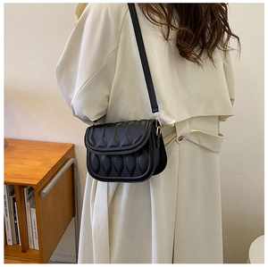 Detail of classic black crossbody bag featuring unique pleated wave texture and flap closure