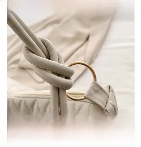 Detail of beige quilted bucket bag with knotted shoulder strap and gold metal rings