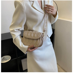 Detail of beige quilted crossbody bag showing wave texture and adjustable shoulder strap