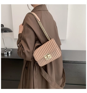 Detailansicht der beigefarbenen Stepptasche mit goldener Kette und edler Metallschließe