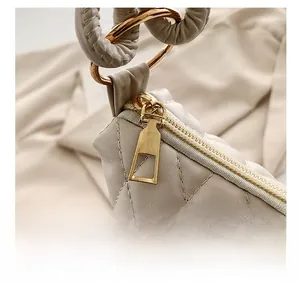 Detailed macro of smooth gold metal zipper and textured off-white quilted bucket bag