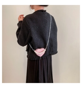 Détail du sac à bandoulière rose en forme de cœur avec perles et chaîne argentée