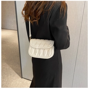 Detail view of a white flap crossbody bag with 3D petal stitching and gold hardware detail