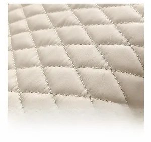 Detailed close-up of quilted beige leather texture with classic diamond stitch pattern