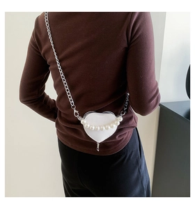 Détail du mini sac blanc en forme de cœur avec perles et chaîne argentée sur modèle