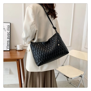 Detailed view of the large black quilted hobo shoulder bag worn on a person's shoulder