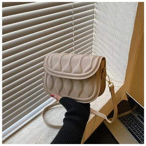 Detail of light beige crossbody bag featuring unique vertical wavy quilted texture and gold hooks
