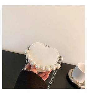 Détail du petit sac blanc en forme de cœur avec anse en perles et chaîne argent