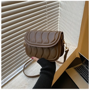 Detail shot of vintage brown quilted leather saddle bag with gold metal hardware