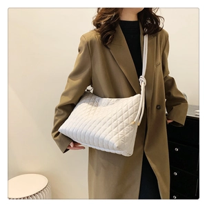 Detailed view of white quilted bucket bag with knotted strap on a fashion model outfit