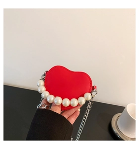Détail d'un mini sac cœur rouge avec poignée en perles et bandoulière chaîne argentée
